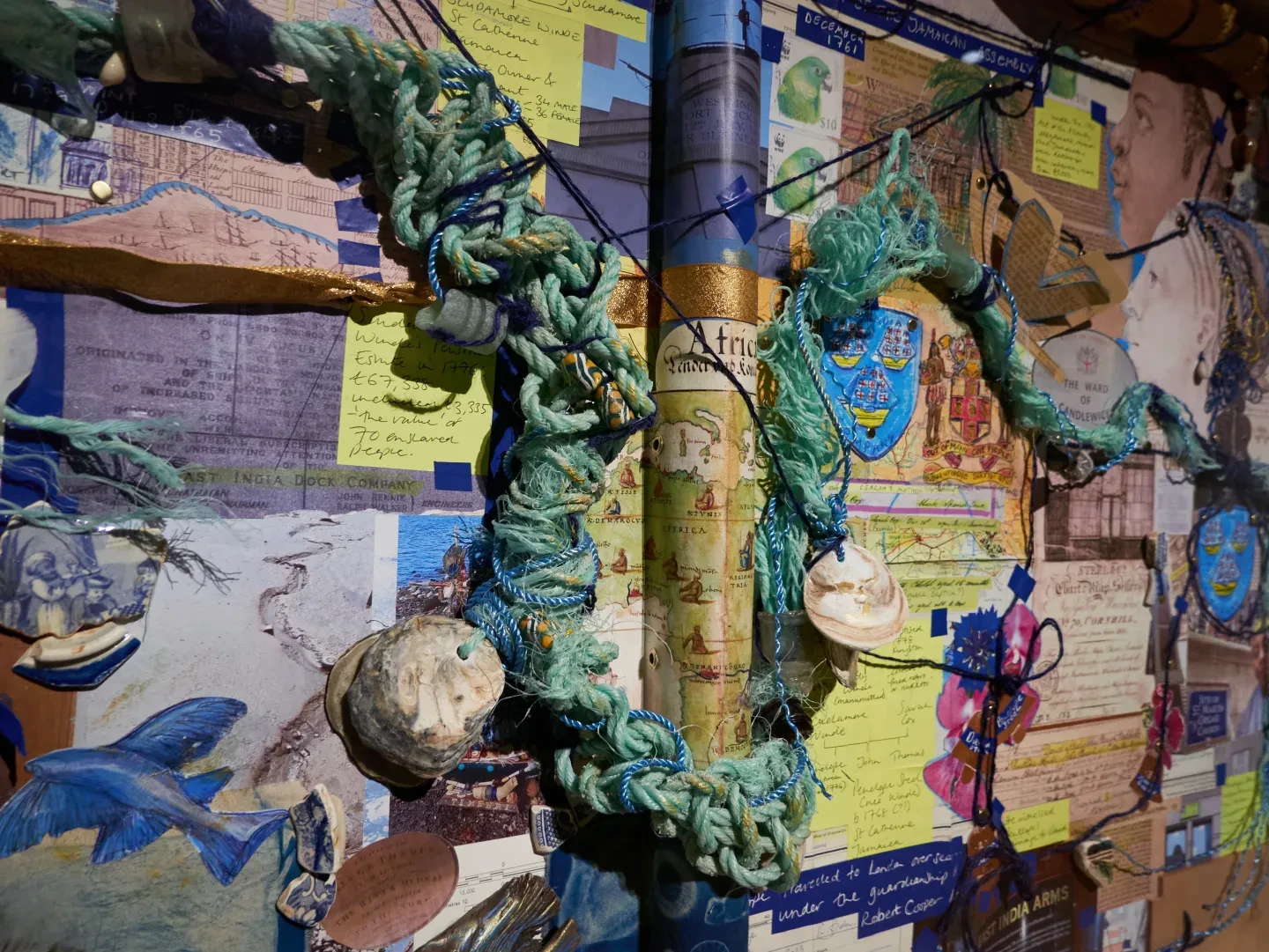 A collage artwork made up of twisted rope, flying fish, shells and images of historic maps and documents